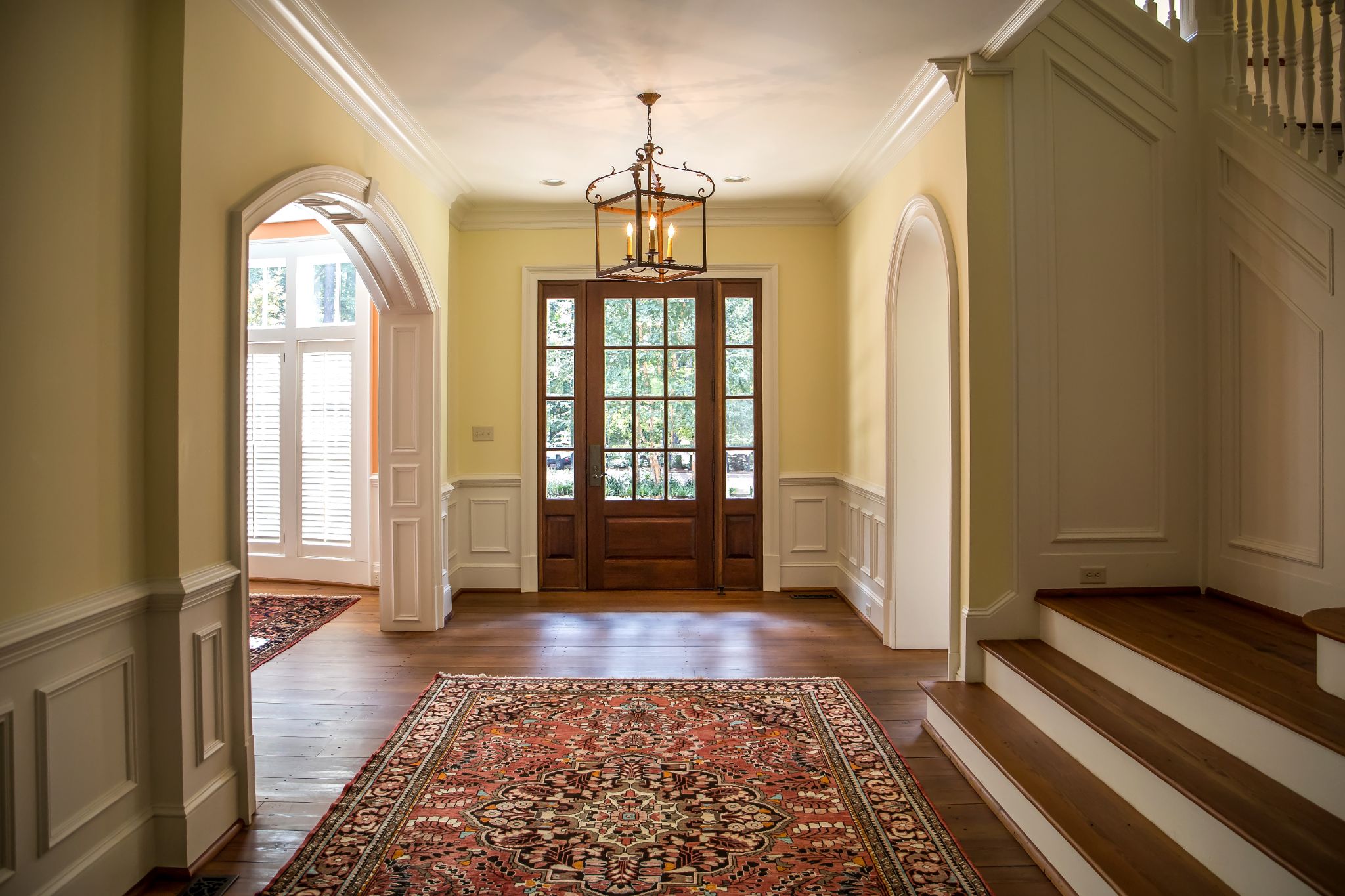 Grand and elegant yellow entrance to a home with stairs.