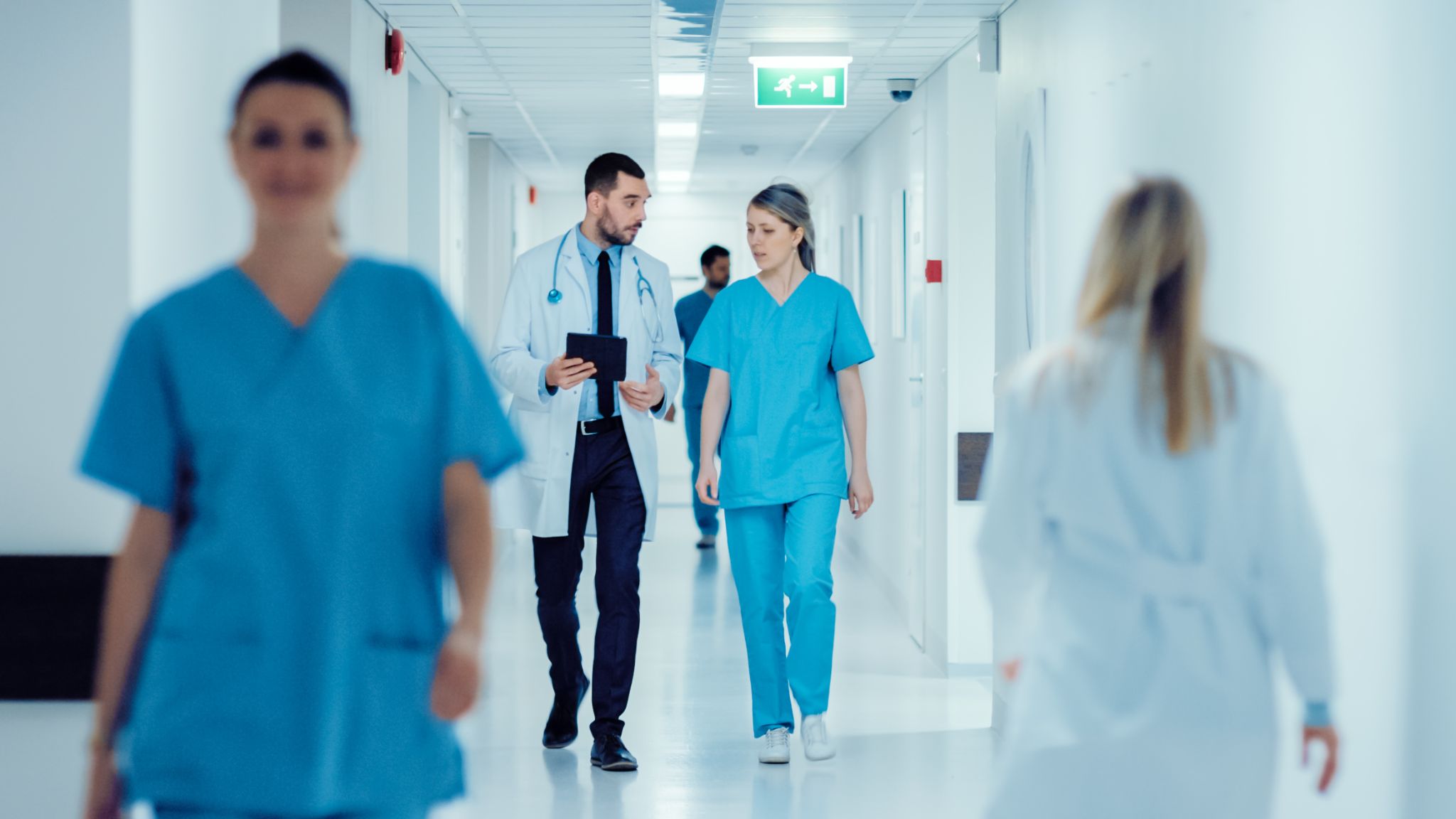 Surgeon and Female Doctor Walk Through Hospital Hallway