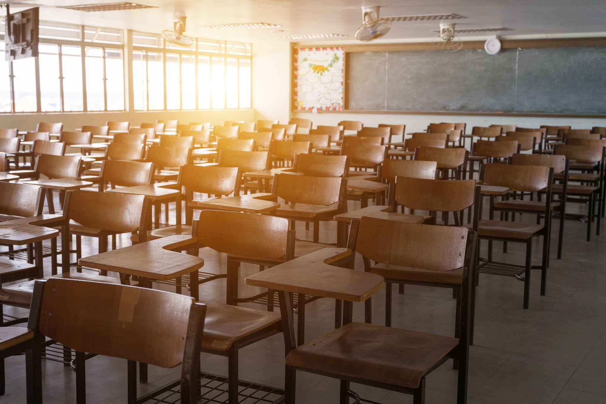 Empty school classroom with many wooden chairs. Wooden chairs in classroom.