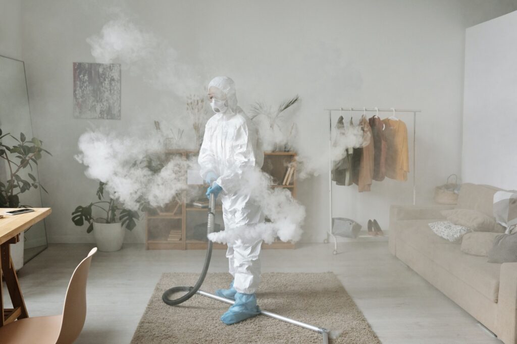 A person disinfecting while wearing a protective suit