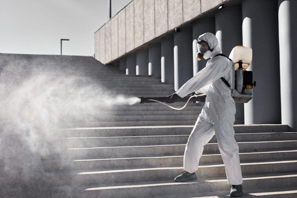professional worker man in white protective suit cleans the stairs with spray