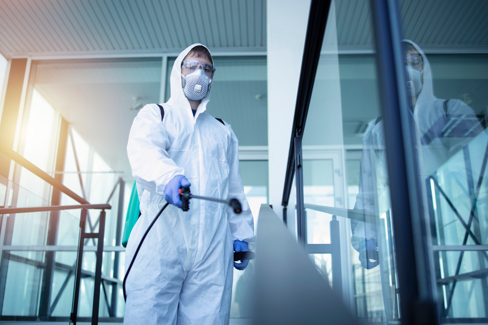 male person in white chemical protection suit doing disinfection of public areas