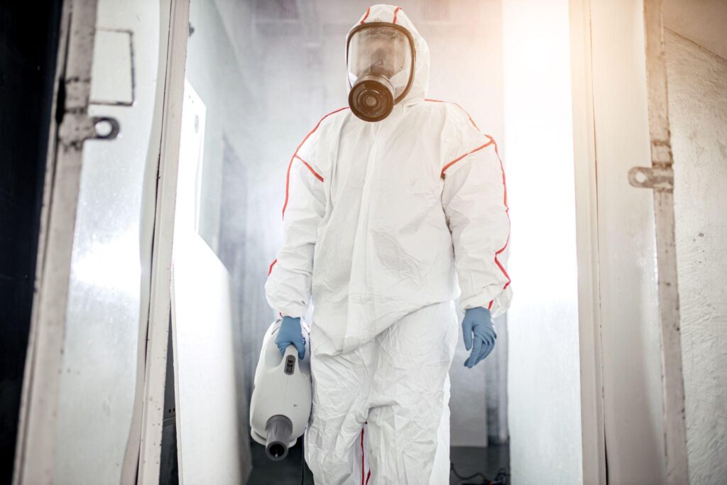 male in protective hazmat suit and gas-mask against coronavirus, disinfect areas